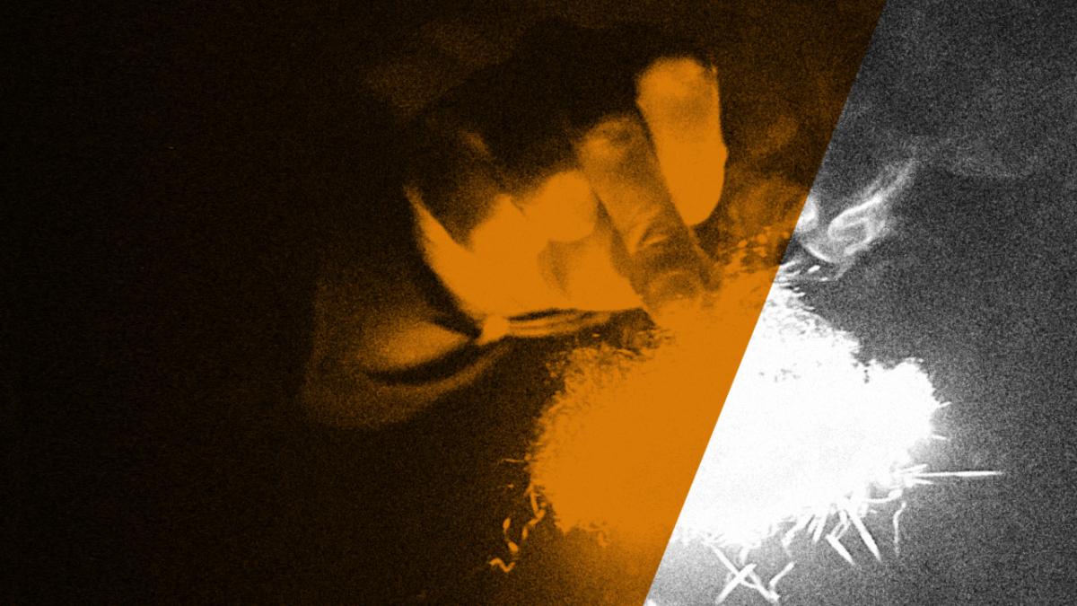 Hazy black and white photo of light and a hand, with orange stripe