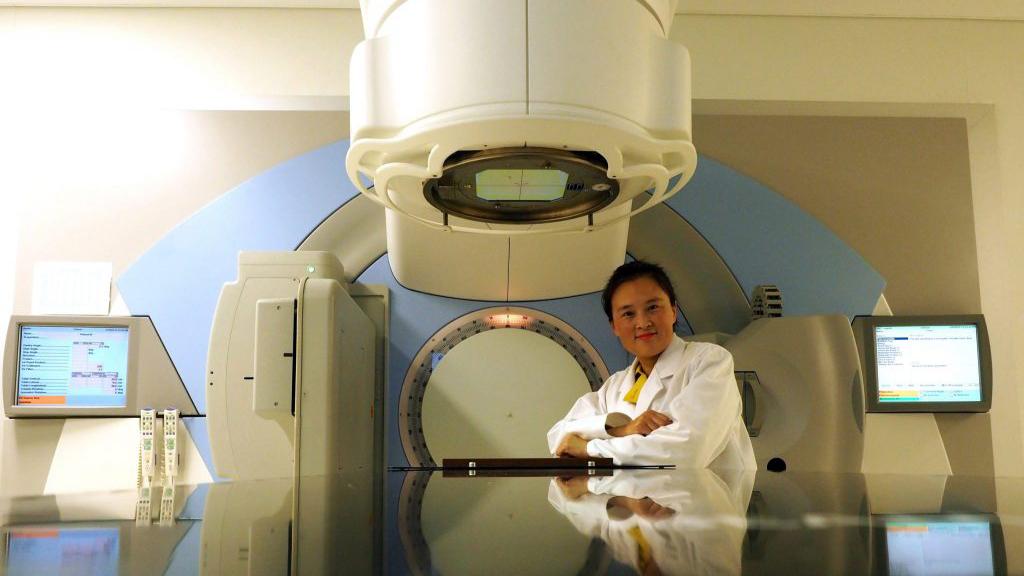 Photo of Wei Deng in front of medical equipment