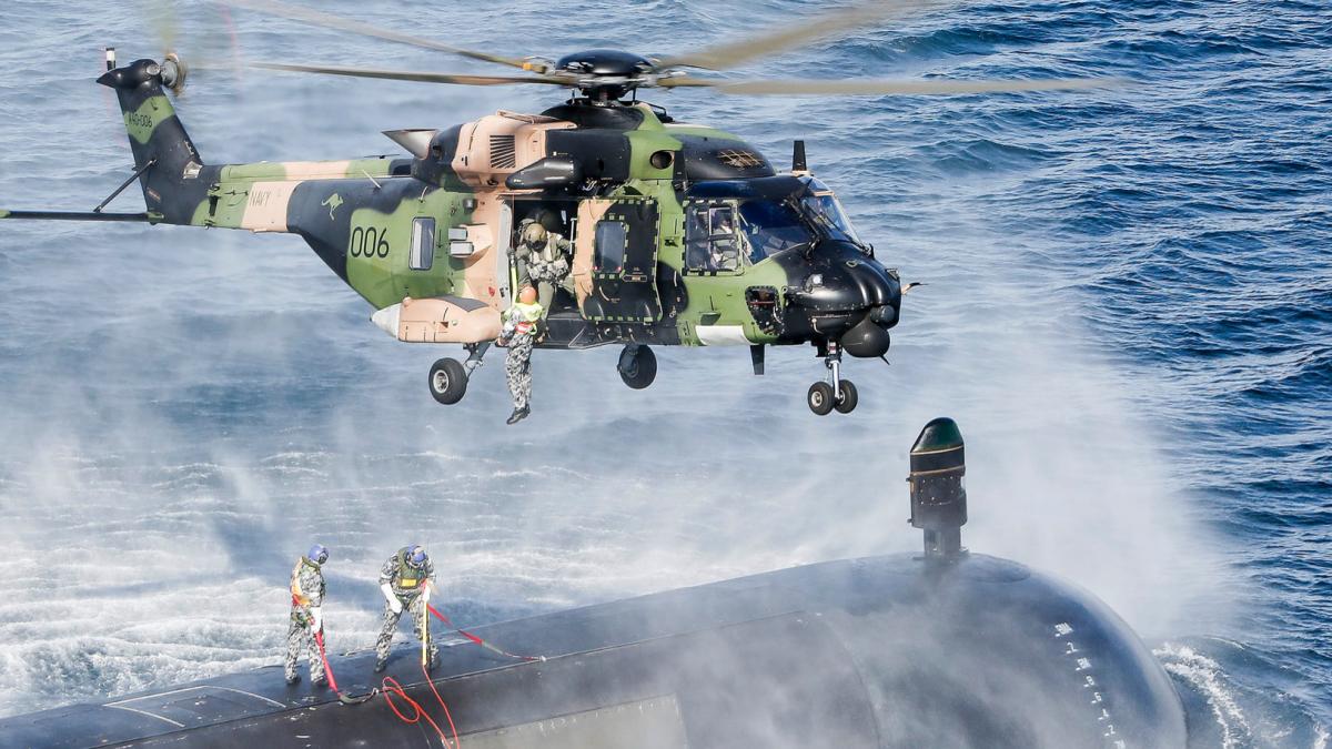photo of a helicopter over a submarine in the ocean