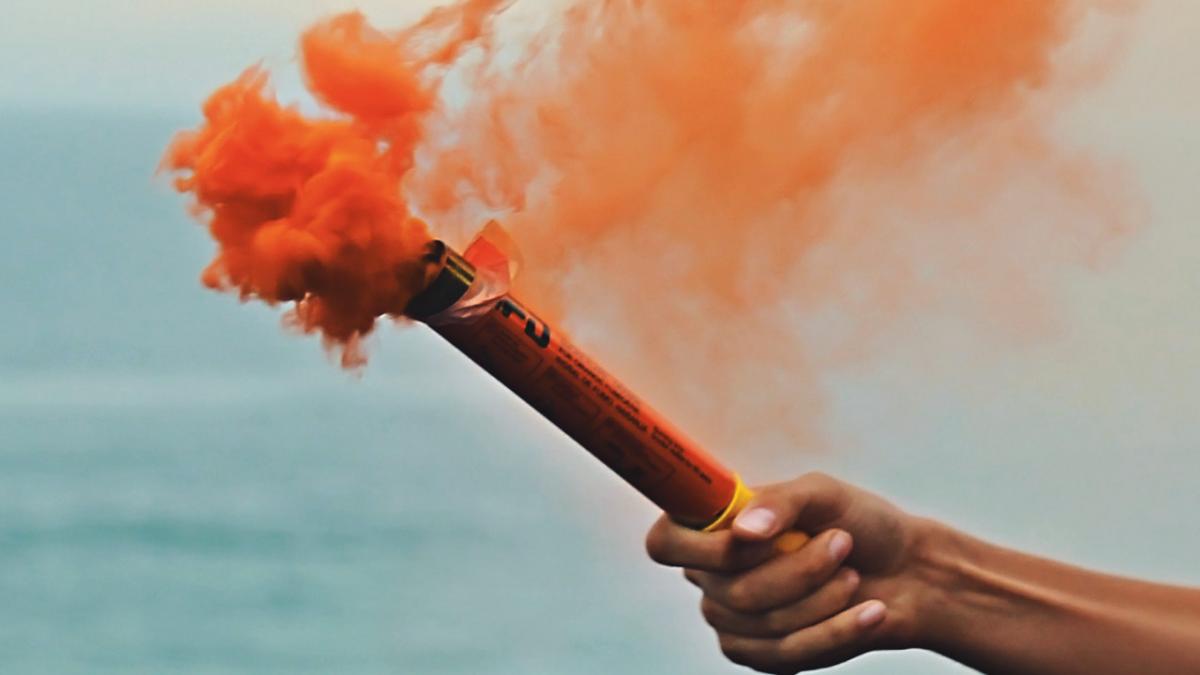 Hand holding up a coloured smoke bomb