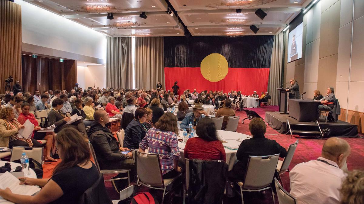 photo of people seated in a room with the Aborginal flag on the wall